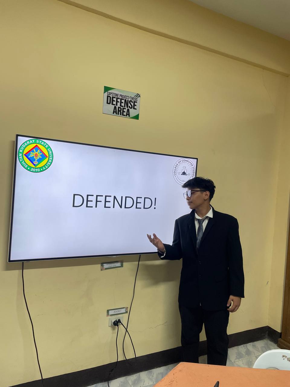Von standing beside the successful capstone defense presentation screen